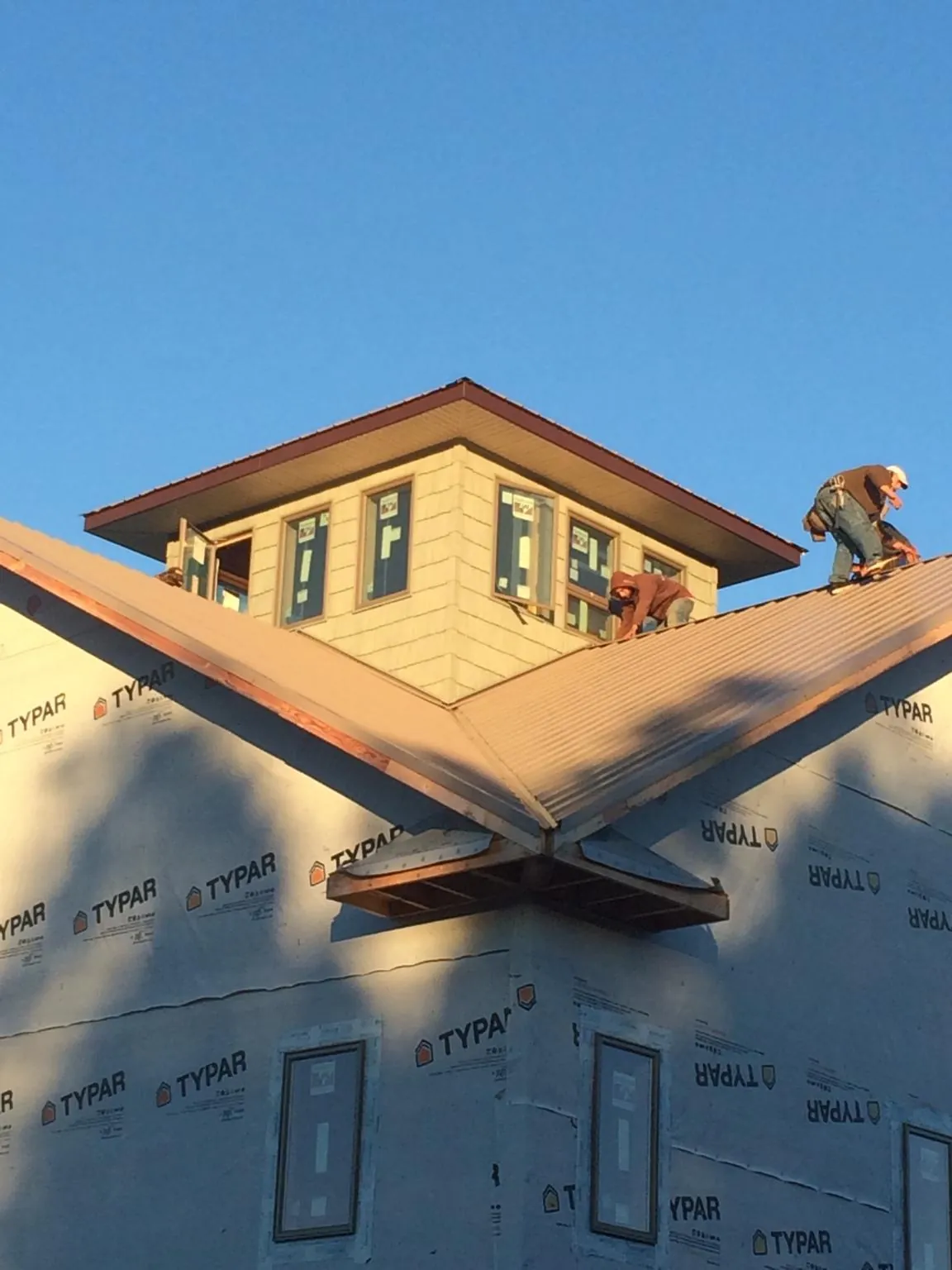 Roofers working around a rooftop cupola on a new metal roof at sunset — Roof Waterproofing in Fontana by Roofing Brothers